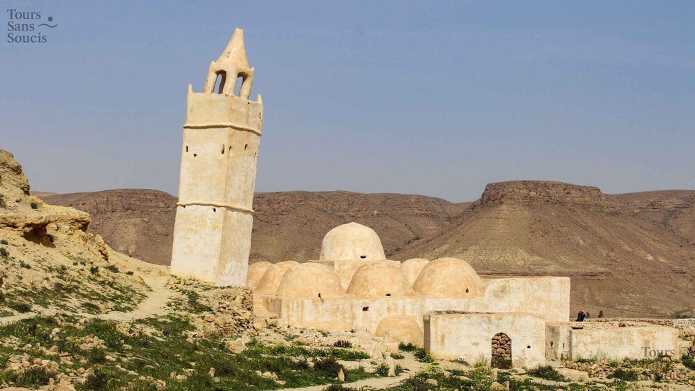 A desert landscape with a prominent minaret and dome structures. 4