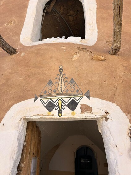 A traditional building with a white facade and a decorative geometric pattern above the entrance. 3