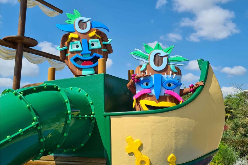 A colorful play structure with two faces on top, a green slide, and a clear blue sky. 4