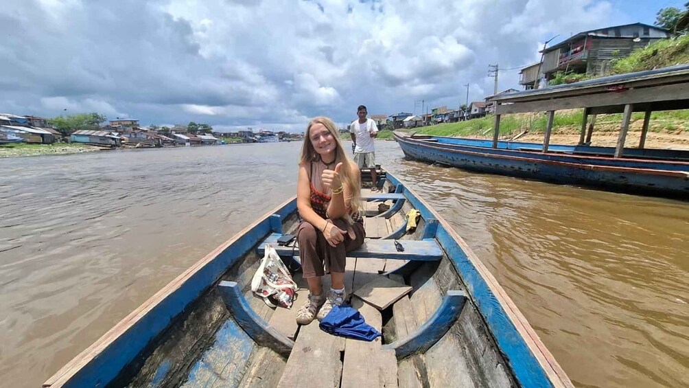 A person in a boat on a river with houses in the background. 2