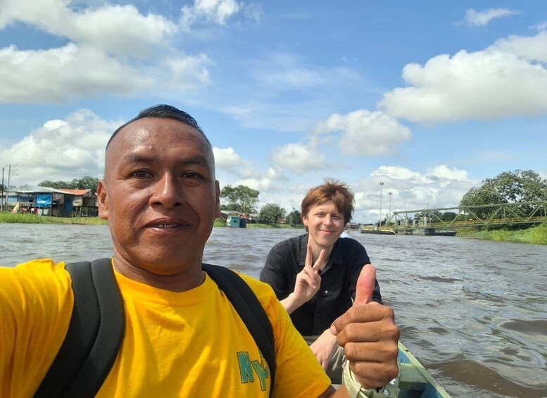 Two people on a boat with a bridge and greenery in the background. 4
