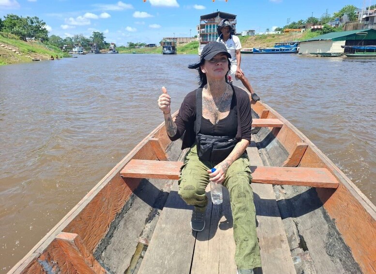 A person in a wooden boat on a river with another person in the background. 3