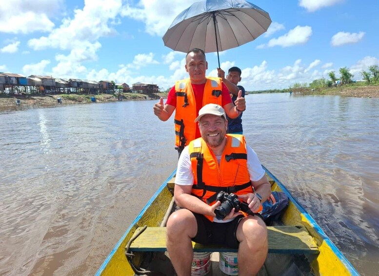 A person in a boat with an umbrella, wearing a life jacket, and another person in the background. 3