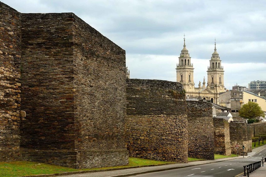 A historic stone wall with a cathedral in the background. 1