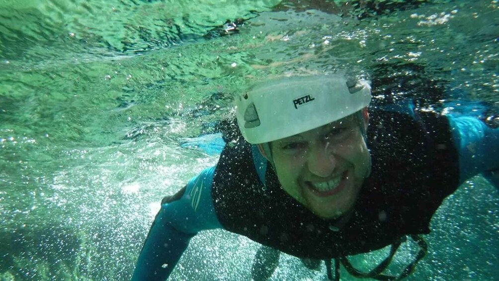 A person underwater wearing a white helmet and a blue jacket. 2