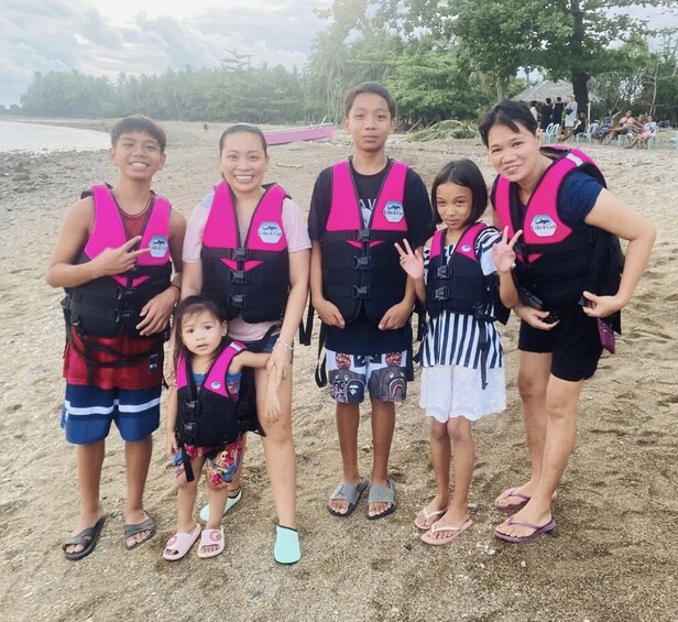 A group of people on a sandy beach with trees in the background. 3