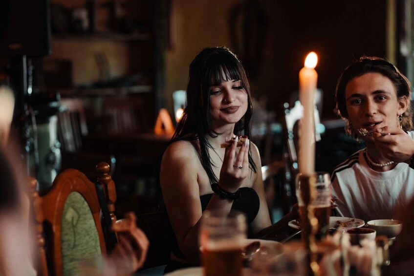 A dimly lit restaurant with a candle on the table, wooden chairs, and a person eating. 3