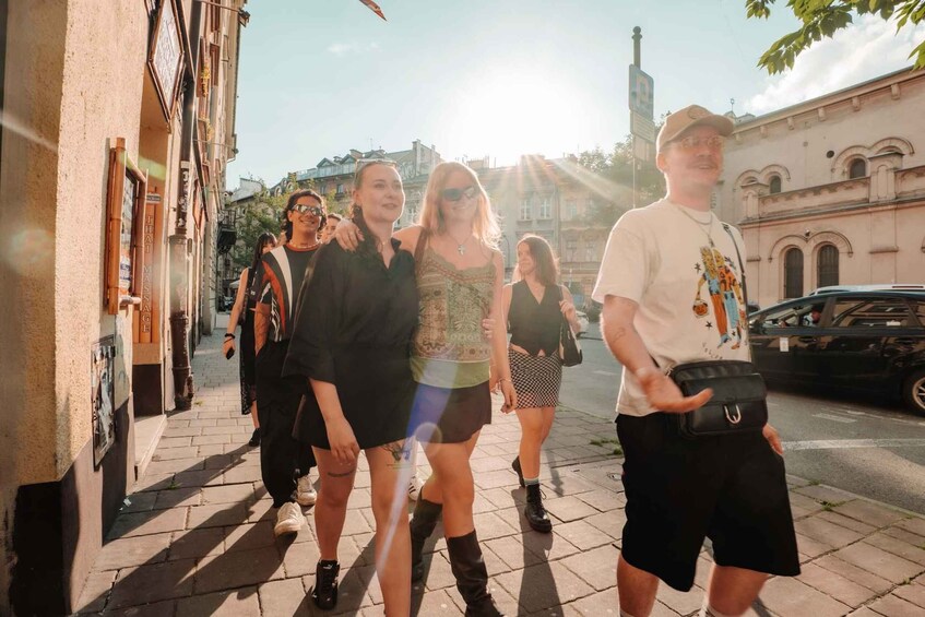 A group of people walking on a city street with buildings and a car in the background. 5