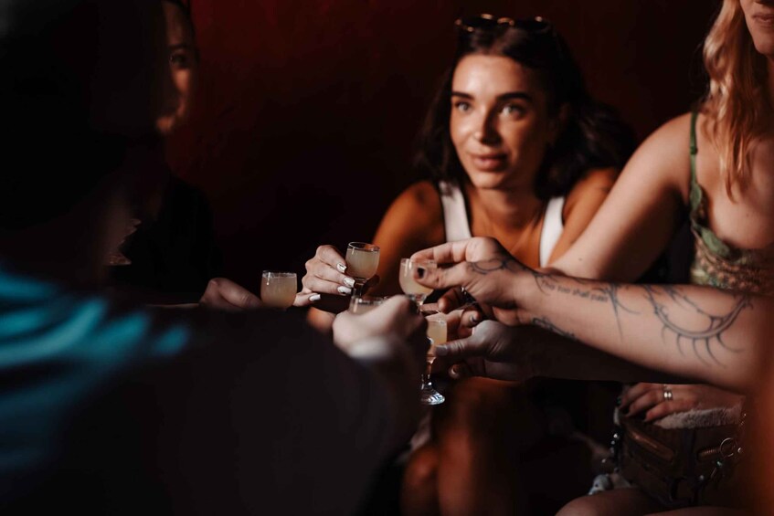 A group of people toasting with drinks in a dimly lit setting. 4