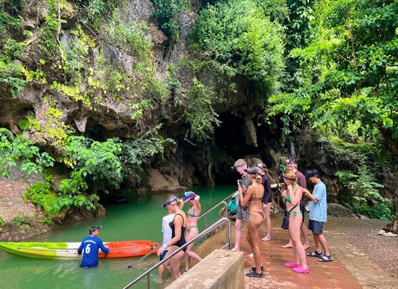 A group of people at a natural water body surrounded by greenery and rocky terrain. 5