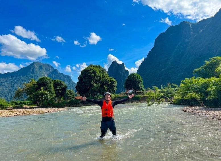 A person wading in a river with mountains in the background. 4