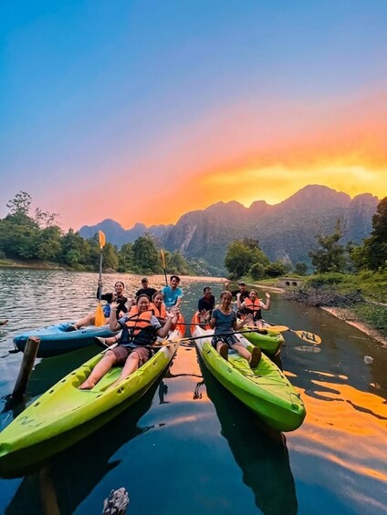 A group of people kayaking on a calm river with mountains in the background during sunset. 3