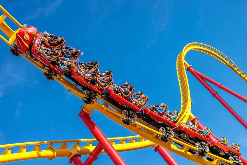 A roller coaster with red cars and yellow tracks against a clear blue sky. 4
