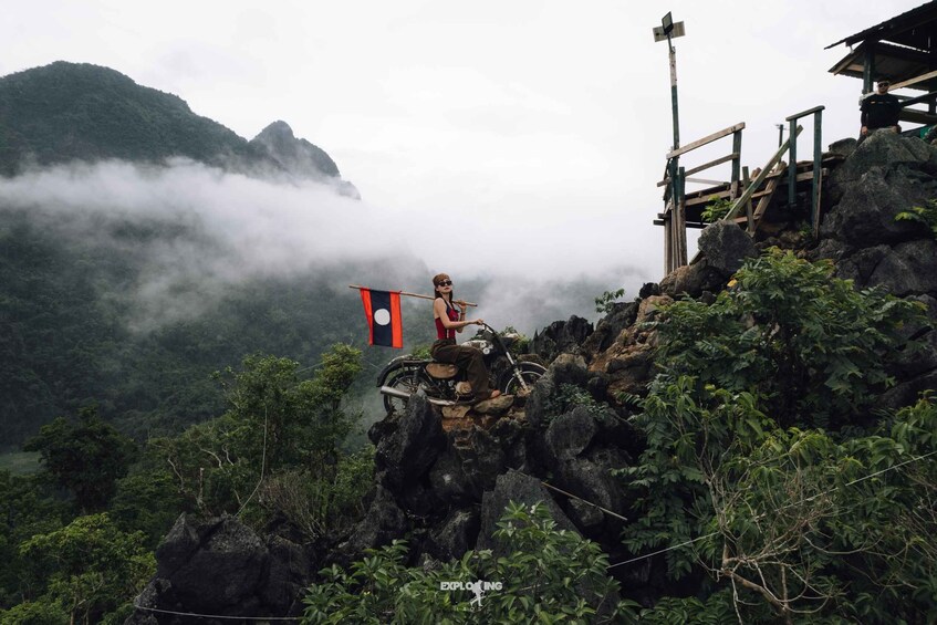 A person on a motorcycle on a rocky mountain with a flag. 3