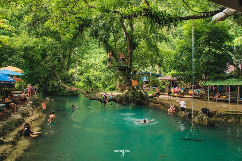 A natural swimming area surrounded by lush greenery, with people engaging in water activities. 2