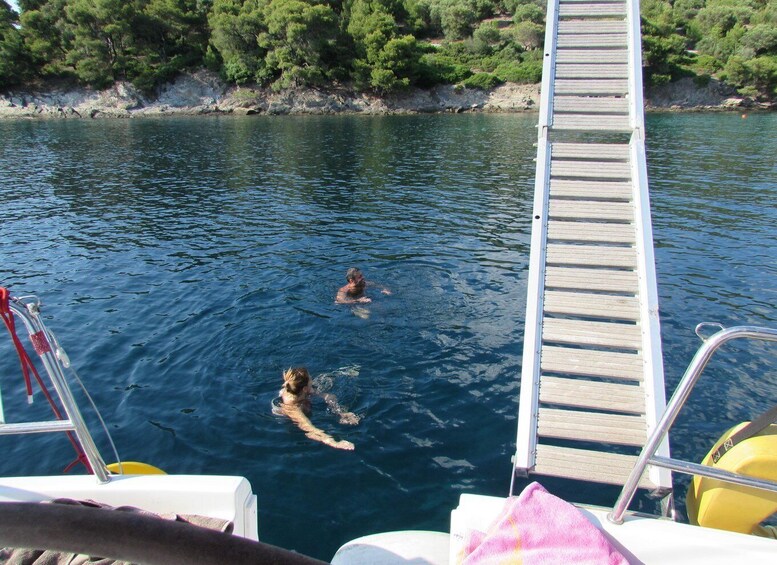 A wooden dock extending into a body of water with two people swimming. 2