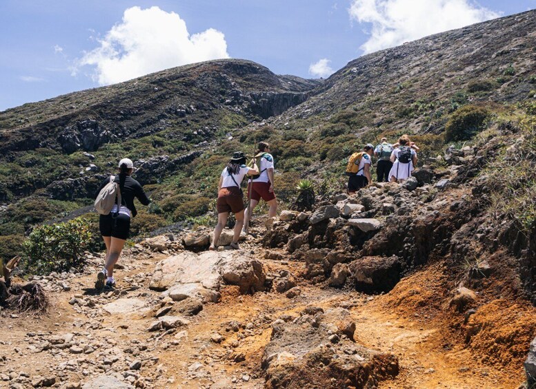 Hikers ascending a rocky mountain trail with sparse vegetation. 2