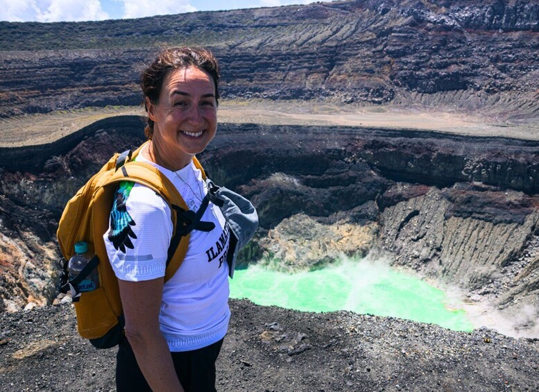 A person standing on a rocky terrain with a large crater in the background. 1