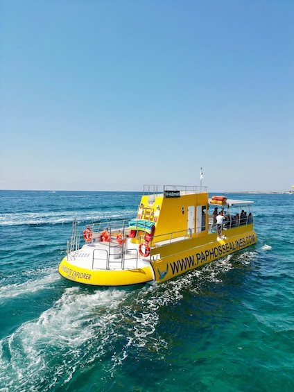 A yellow boat named 'Paphos Explorer' with passengers and lifebuoys on a clear blue sea. 3