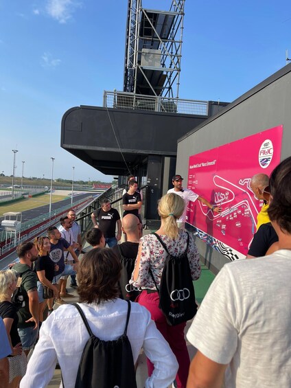 A group of people at a sports event, standing near a large pink advertisement board. 4