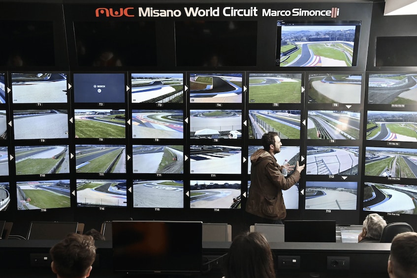 A control room with multiple monitors displaying various angles of a racing circuit. 2