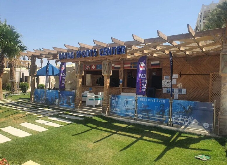 The Diving Sports Center with a wooden pergola entrance, flags, and promotional banners. 5