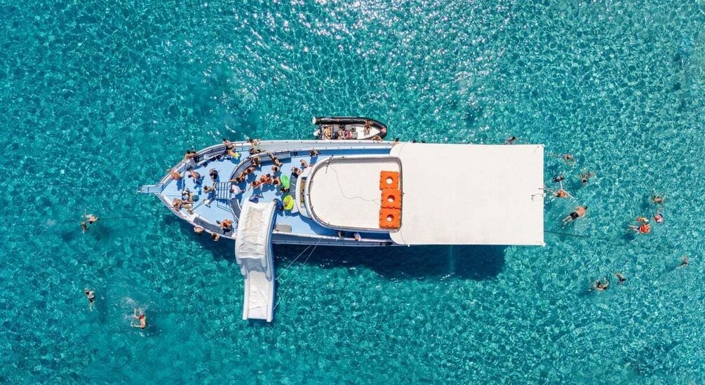 A boat with people swimming in the water around it. 3