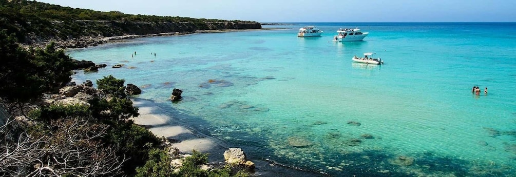 A coastal landscape with clear turquoise waters, rocky shores, and boats. 2