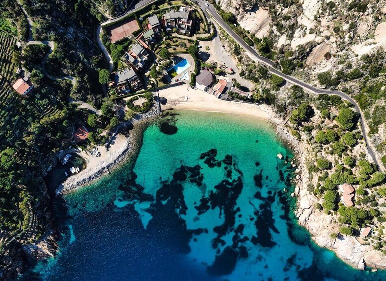 An aerial view of a coastal resort with clear turquoise waters, a sandy beach, and lush greenery. 3