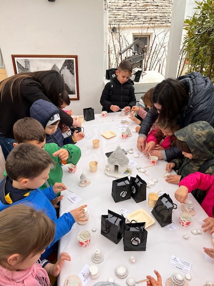 Children engaged in a craft activity at a table, surrounded by various crafting materials and small decorative items. 1