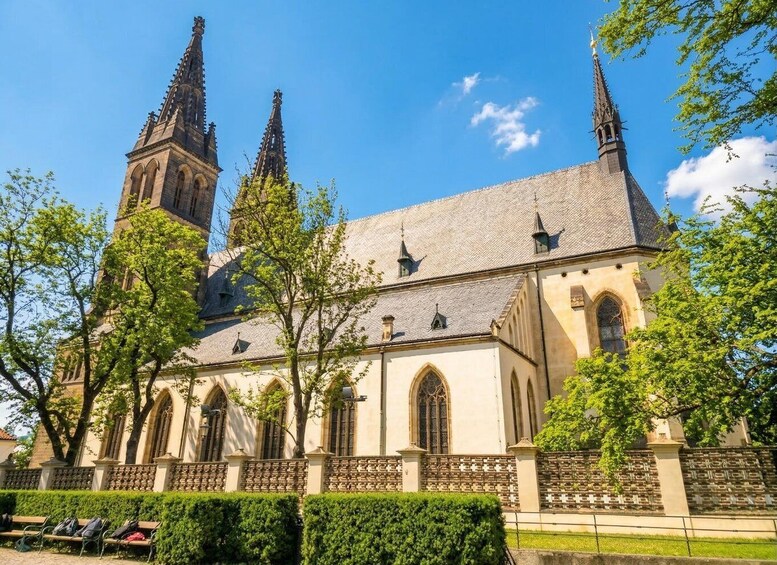A historic church with two tall spires, arched windows, and a brick wall with crosses. 1