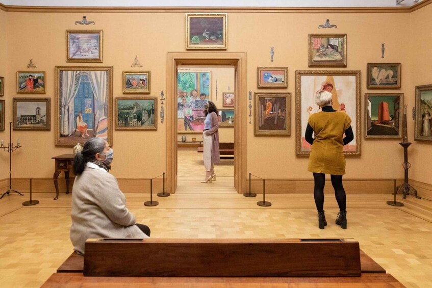 An art gallery with paintings on the walls and a person standing in front of a painting. 1