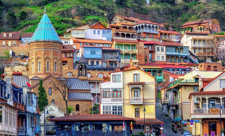 A colorful hillside town with a prominent church tower and a variety of traditional buildings. 3