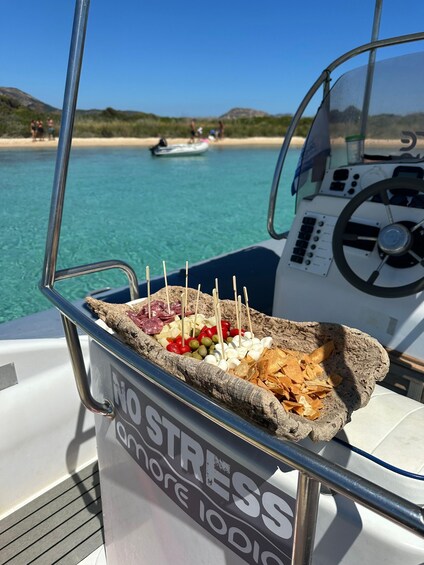 A boat with a stone tray holding food items like olives, cheese, and chips. 5