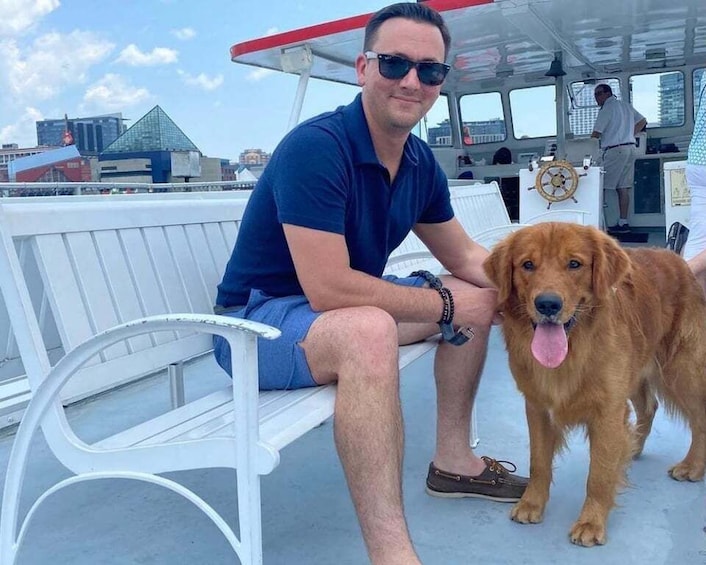 A man sitting on a white bench with a golden retriever on a boat. 2