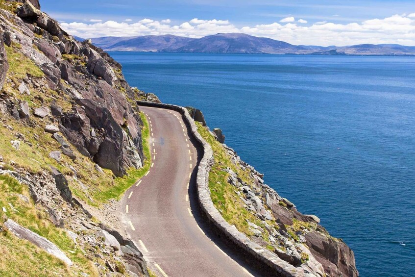 A winding coastal road with rocky cliffs and a clear blue sea. 5