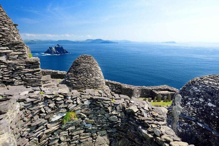 A stone structure with a conical roof overlooking a calm sea and distant islands. 3