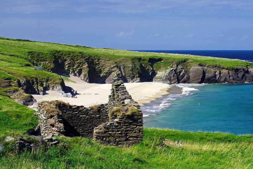 A coastal landscape with cliffs, a sandy beach, and a stone ruin. 1