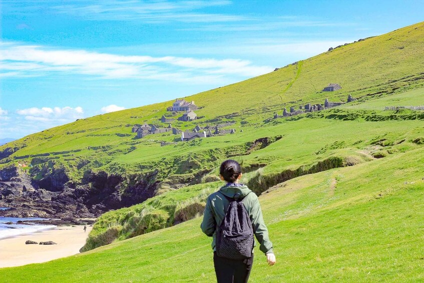 A hiker walking on a grassy hillside with a coastal landscape in the background. 4