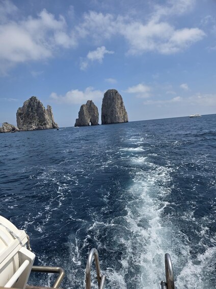 A boat moving through the ocean with two large rock formations in the distance. 2