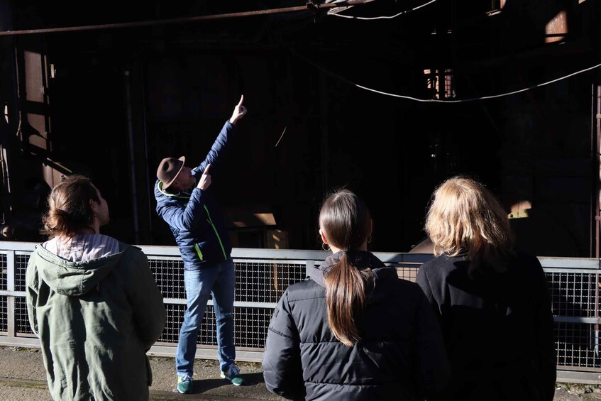 A person pointing towards a building with a metal fence in the foreground. 2