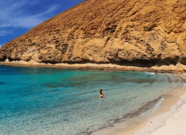 A beach with clear turquoise water, a sandy shore, and a rocky cliff. 4