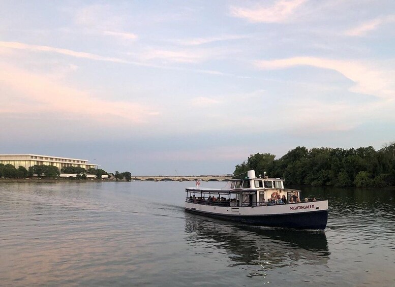 A boat named 'NIGHTINGALE II' on a river with a bridge and trees in the background. 2