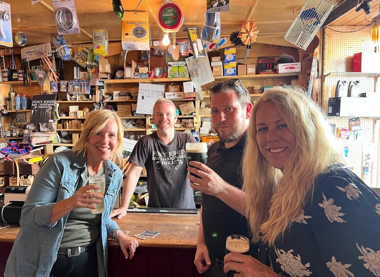 A bar with wooden shelves stocked with various items, including a sign for Foxy John's Bar Hardware. 1