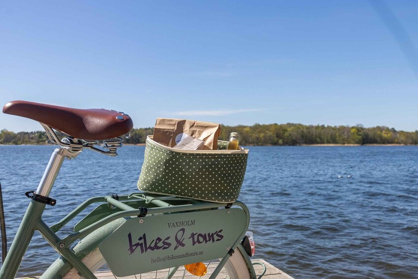 A bicycle with a basket containing bags and a sign that reads 'VAXHOLM bikes & tours.' 1