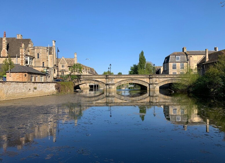 A stone bridge over a calm river, surrounded by historic buildings. 4