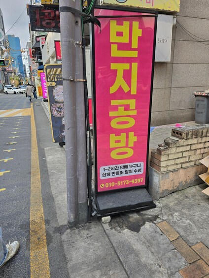 A street with a red signboard, a digital display, and a brick wall. 3