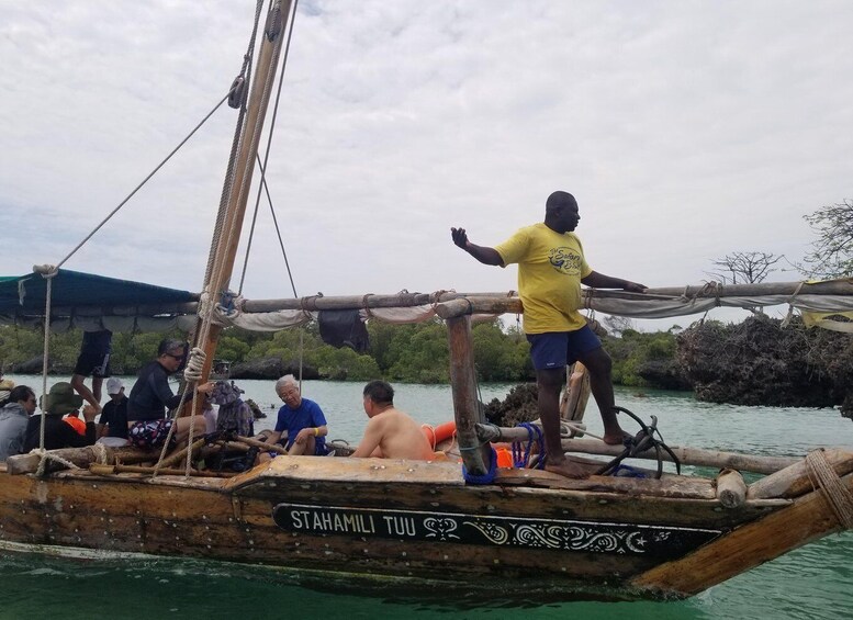 A traditional wooden boat with people on board, surrounded by calm water and greenery. 3