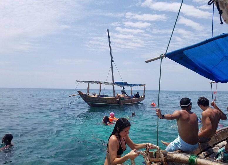 A boat with people on it, a person swimming, and another person on a float in the water. 1