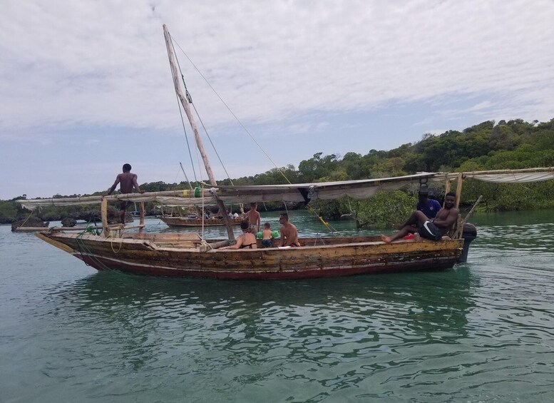 A traditional wooden boat with people on it, surrounded by calm water and greenery in the background. 2